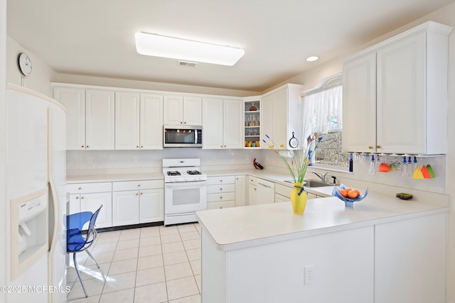 kitchen with white appliances, light tile patterned floors, a peninsula, decorative backsplash, and light countertops