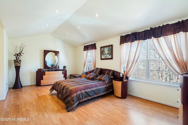 bedroom with baseboards, multiple windows, lofted ceiling, and light wood finished floors