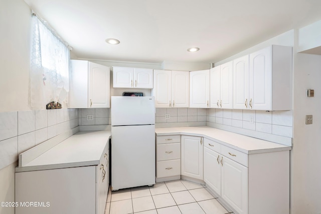 kitchen featuring white cabinetry, light tile patterned flooring, and freestanding refrigerator