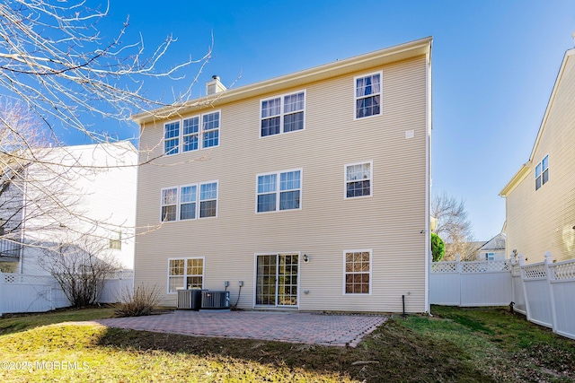 rear view of property featuring central AC unit, a yard, a patio area, and a fenced backyard