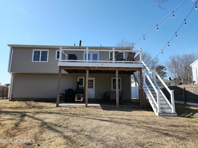 back of property featuring stairs, fence, a lawn, and a wooden deck