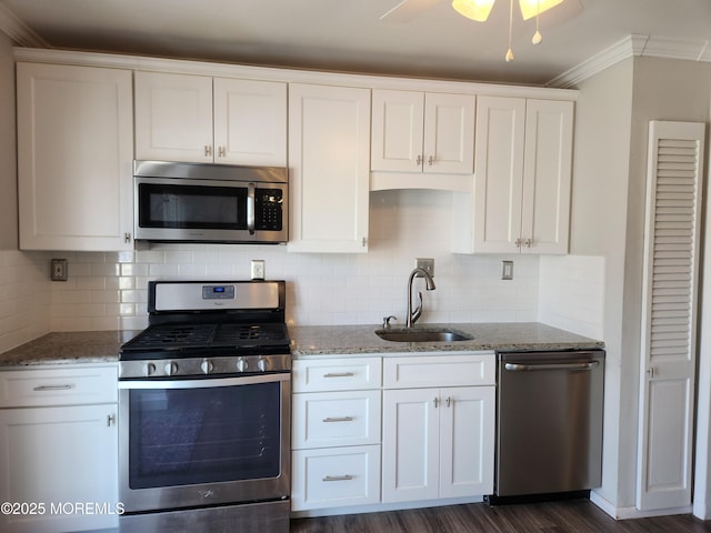 kitchen featuring dark wood-type flooring, a sink, light stone counters, white cabinetry, and stainless steel appliances