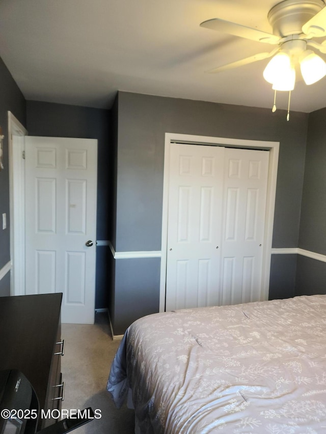 carpeted bedroom featuring a ceiling fan, a closet, and baseboards
