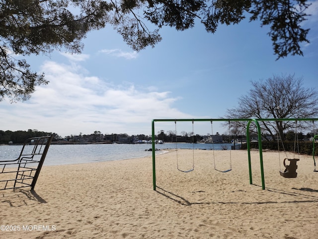 surrounding community with playground community and a water view