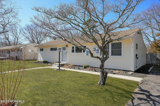 ranch-style home with a front yard and fence