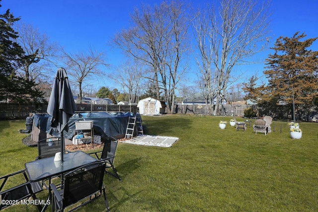 view of yard with a fenced in pool, an outbuilding, a storage shed, and a fenced backyard