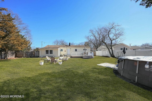 back of property featuring a lawn, a wooden deck, and a fenced backyard