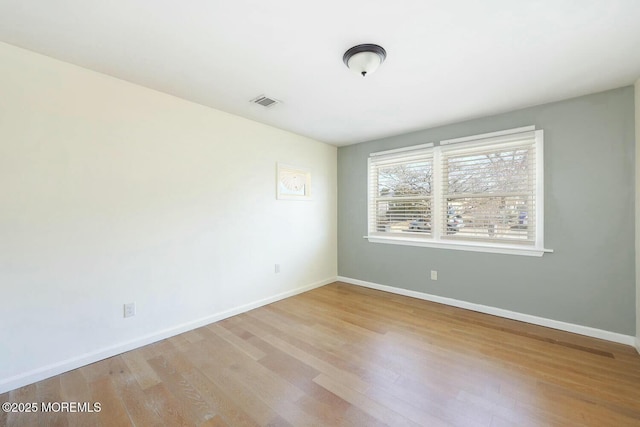 empty room featuring visible vents, baseboards, and wood finished floors