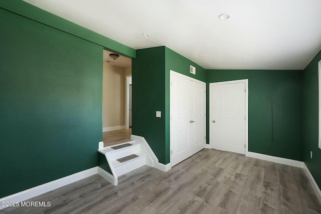 unfurnished bedroom featuring a closet, baseboards, visible vents, and wood finished floors