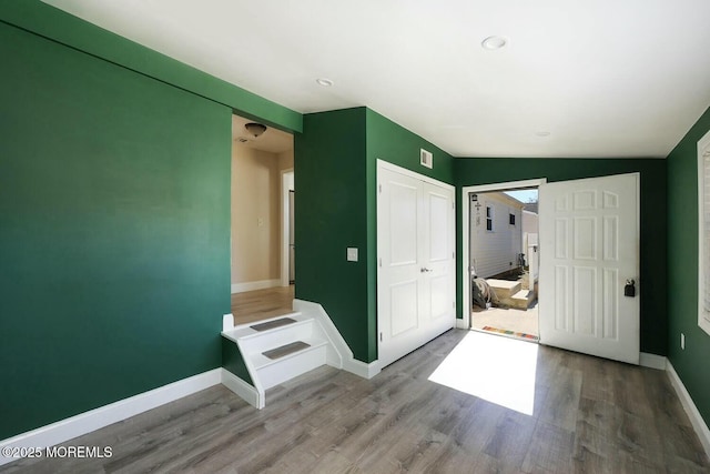 unfurnished bedroom featuring visible vents, wood finished floors, baseboards, and a closet