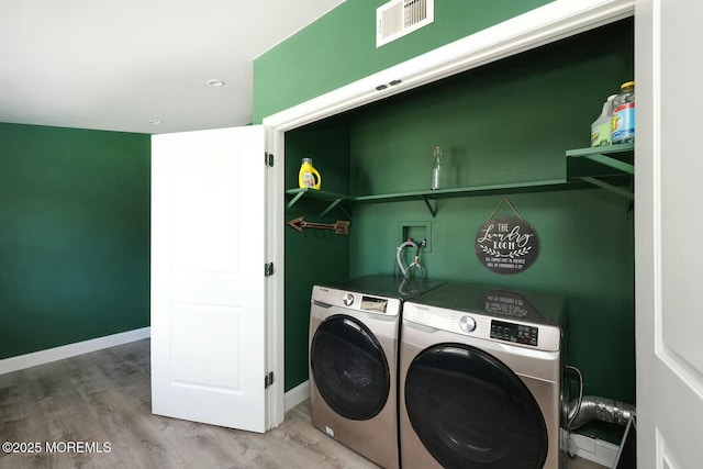 clothes washing area with visible vents, baseboards, laundry area, wood finished floors, and independent washer and dryer