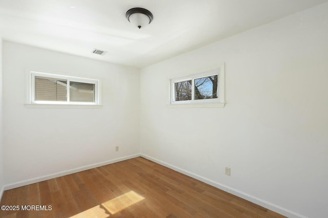 unfurnished room with visible vents, baseboards, and wood finished floors