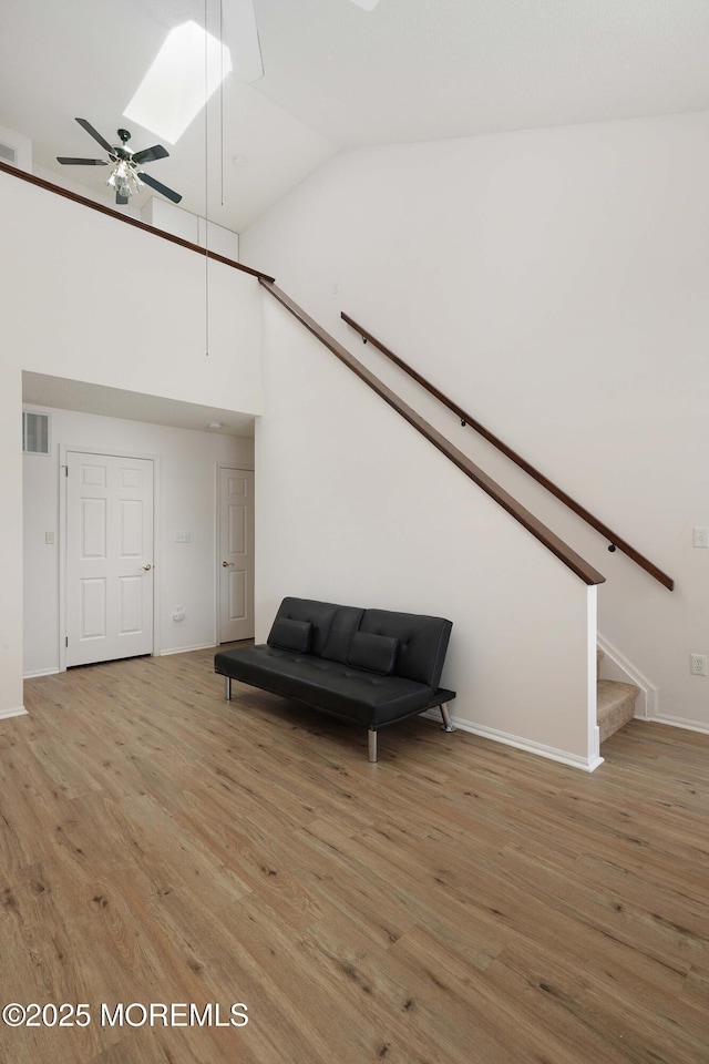 sitting room with visible vents, a skylight, light wood finished floors, ceiling fan, and stairs