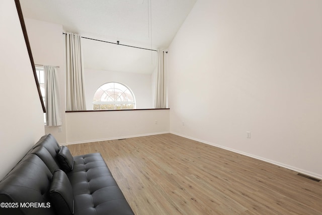 unfurnished living room featuring visible vents, baseboards, lofted ceiling, and wood finished floors