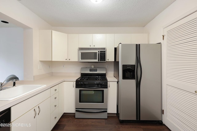 kitchen with dark wood-style flooring, stainless steel appliances, light countertops, and a sink