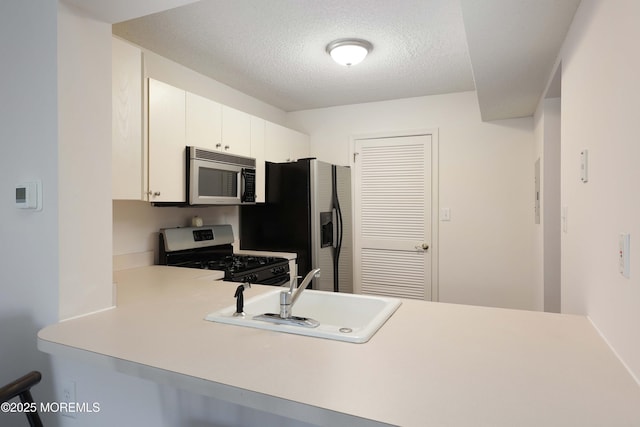 kitchen featuring a sink, stainless steel appliances, a peninsula, and light countertops