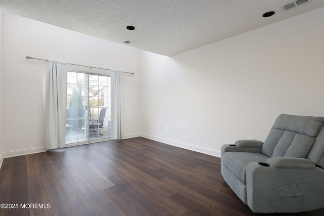 sitting room featuring visible vents, a textured ceiling, dark wood-type flooring, and baseboards