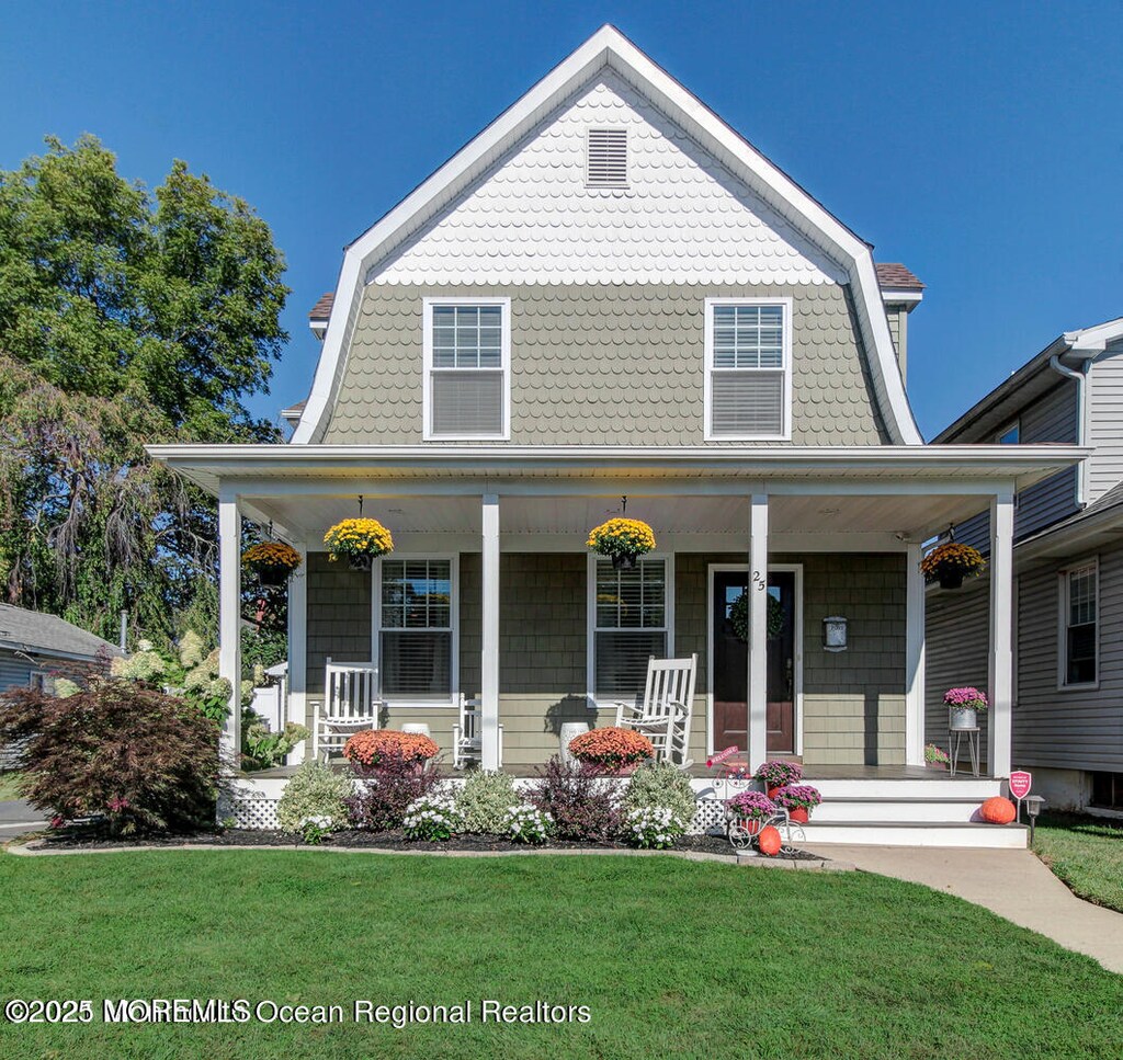 view of front of house with a porch, a gambrel roof, and a front yard