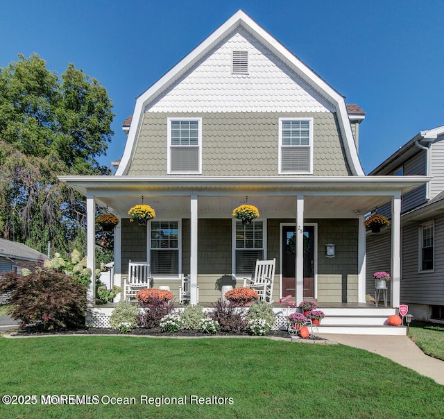 view of front of house with a porch, a gambrel roof, and a front yard