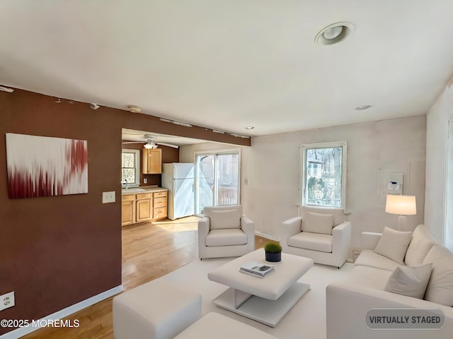 living area featuring baseboards and light wood finished floors