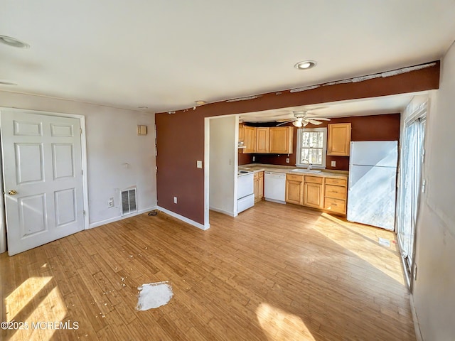 kitchen with white appliances, visible vents, a sink, light countertops, and light wood-type flooring