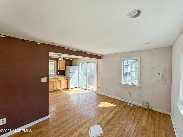 spare room with visible vents, ceiling fan, baseboards, light wood-type flooring, and a sink