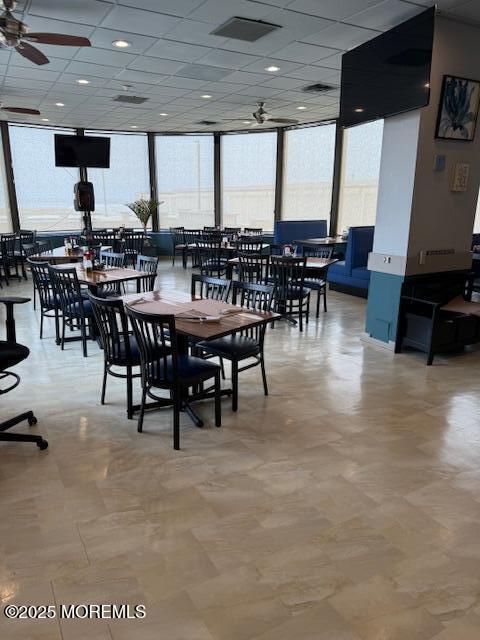 dining space featuring a drop ceiling, visible vents, ceiling fan, and floor to ceiling windows