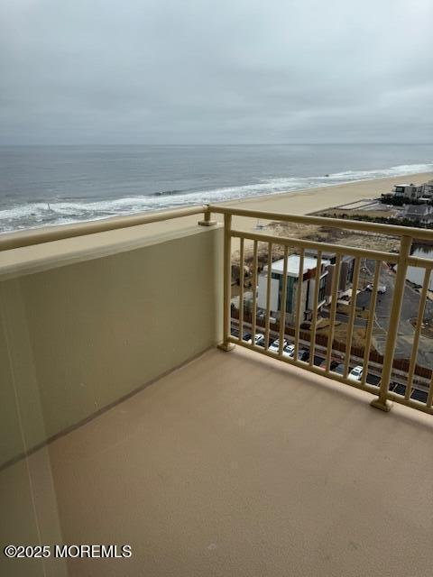 balcony featuring a water view and a beach view