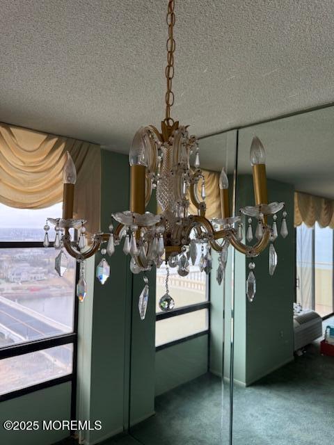 room details featuring a notable chandelier, carpet, and a textured ceiling