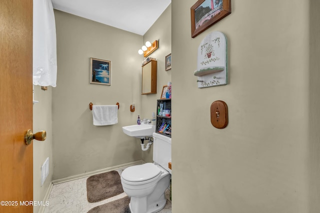 bathroom featuring visible vents, toilet, baseboards, and a sink