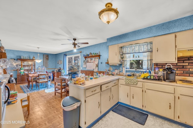 kitchen featuring under cabinet range hood, light countertops, a peninsula, cream cabinets, and a ceiling fan