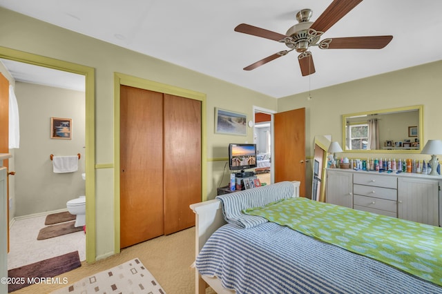 carpeted bedroom with a closet, ensuite bathroom, and ceiling fan