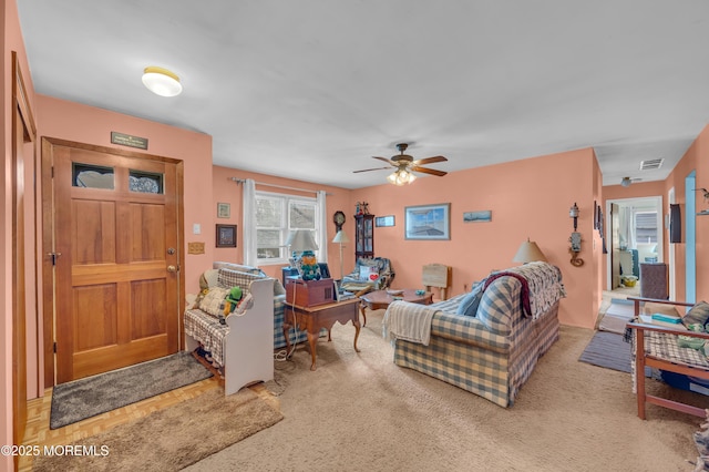 living room with visible vents, ceiling fan, and carpet floors