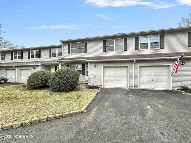 view of property featuring a front lawn, an attached garage, and driveway