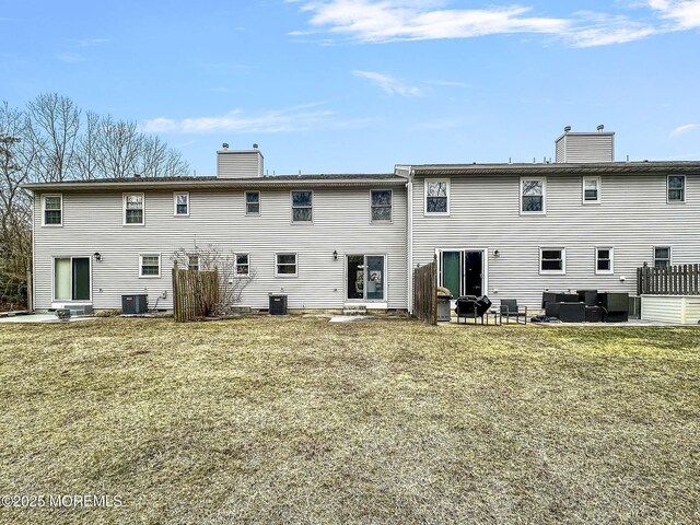 rear view of house featuring central AC unit, an outdoor living space, a chimney, and a patio