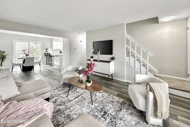 living room with baseboards, a textured ceiling, wood finished floors, and stairs