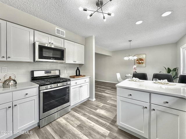 kitchen with light countertops, visible vents, appliances with stainless steel finishes, and a chandelier