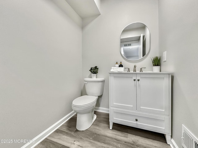 bathroom featuring visible vents, toilet, wood finished floors, baseboards, and vanity