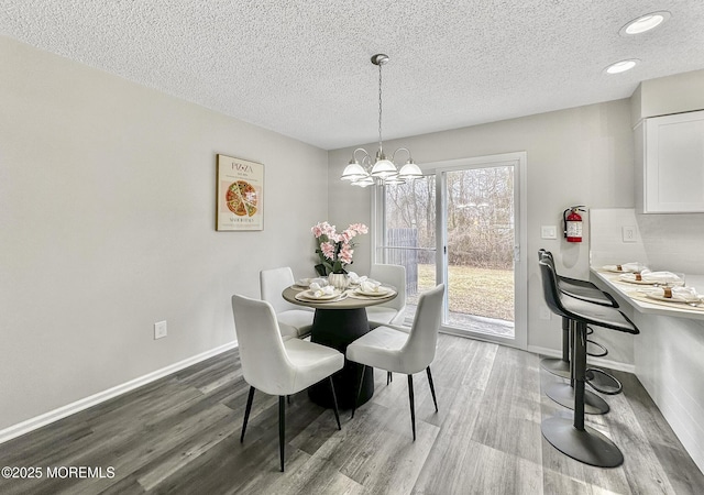 dining room featuring baseboards, a notable chandelier, wood finished floors, and a textured ceiling