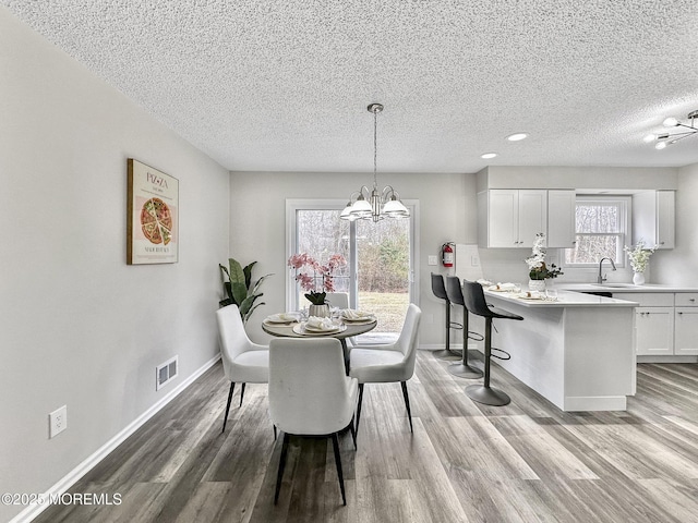 dining space with baseboards, wood finished floors, and a chandelier