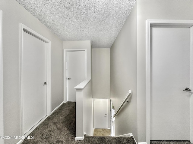 stairs featuring carpet, baseboards, and a textured ceiling