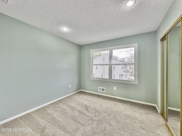 unfurnished bedroom with visible vents, carpet floors, baseboards, a closet, and a textured ceiling