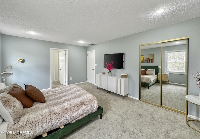 carpeted bedroom with a closet, visible vents, a textured ceiling, and baseboards