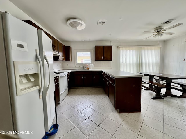 kitchen featuring visible vents, under cabinet range hood, light countertops, a peninsula, and white appliances