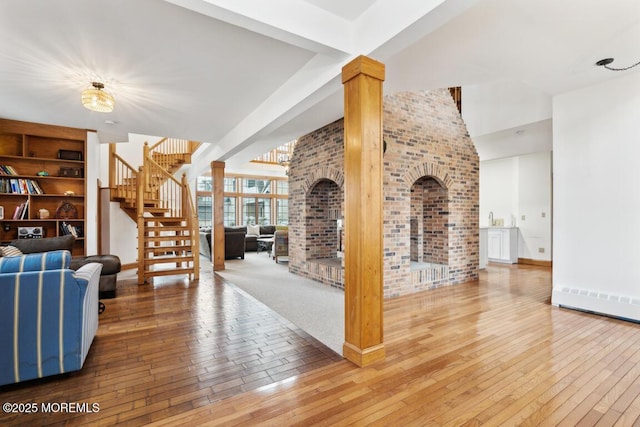 living room featuring brick wall, stairs, baseboards, and hardwood / wood-style floors