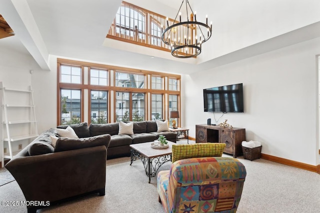 carpeted living room featuring an inviting chandelier, baseboards, and a towering ceiling