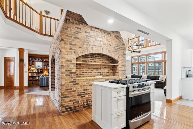 kitchen with light wood-type flooring, visible vents, gas range, and an inviting chandelier