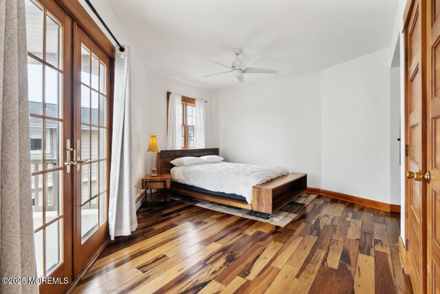 bedroom featuring baseboard heating, ceiling fan, baseboards, and hardwood / wood-style floors