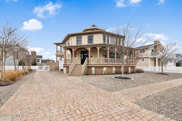 view of front of house with decorative driveway, fence, a porch, and a gate