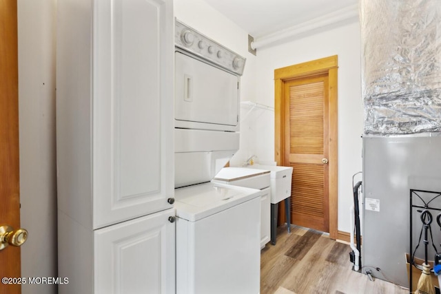 washroom featuring laundry area, stacked washer and dryer, and light wood-style flooring